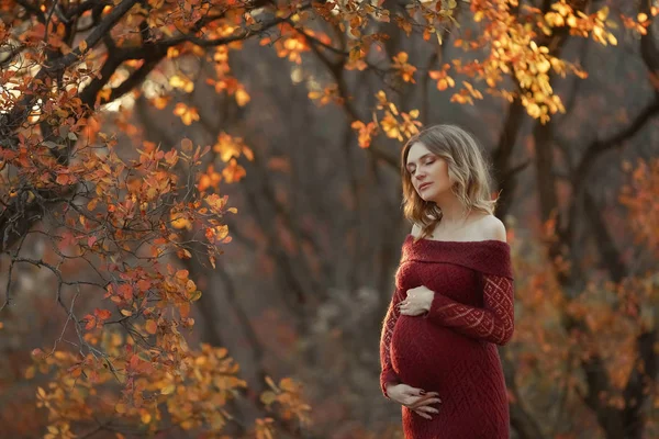 Piękna kobieta w ciąży z blond włosami w długiej czerwonej sukni — Zdjęcie stockowe