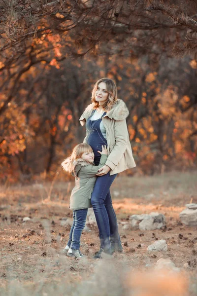 Беременная мать обнимает своего ребенка во время прогулки в парке — стоковое фото
