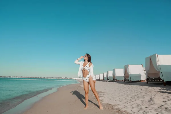 Eine schöne Frau mit sexy durchtrainiertem Körper im modischen Bikini, die es sich am Meeresrand gemütlich macht. Weibchen mit langen Beinen — Stockfoto