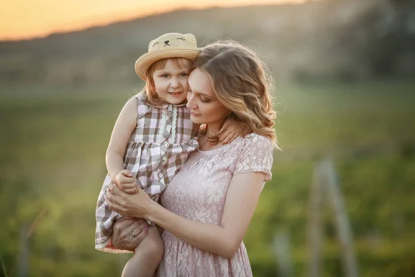 En lycklig familjevandring historia. mor och barn kramar i en äng gula blommor på naturen på sommaren — Stockfoto