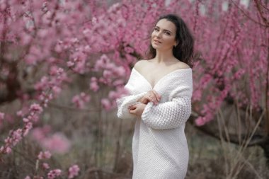 Çiçek açan çalılıklarda bir bayan. beyaz kazak ve etek kadın.