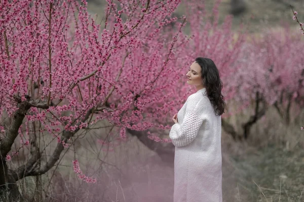 Dame dans les buissons en fleurs. femme en pull blanc et jupe . — Photo