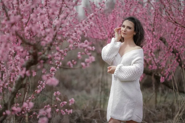 咲く茂みの中の女性。白いセーターとスカートの女性. — ストック写真