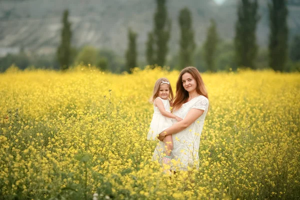 Счастливая мать и дочь с желтыми цветами одуванчиков в летний день — стоковое фото