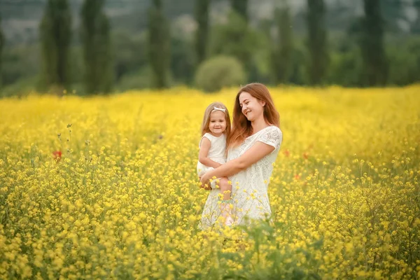 Happy mother and daughter child together with yellow dandelion flowers in summer day — Stock Photo, Image