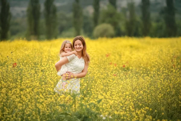 Happy mother and daughter child together with yellow dandelion flowers in summer day — Stock Photo, Image