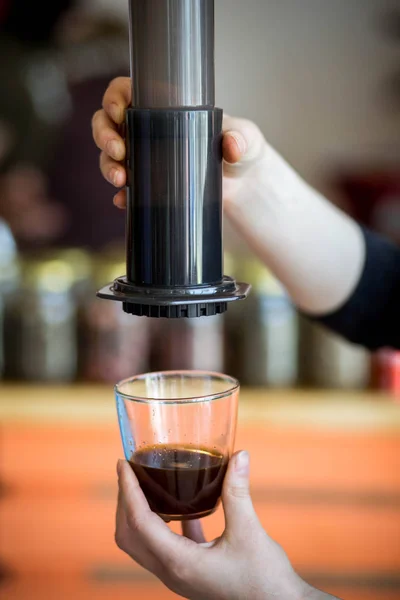 Man preparing coffee in French press coffee maker in warm morning light.