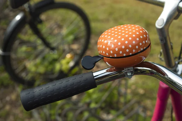 Detail of an orange bicycle ring bell outdoors