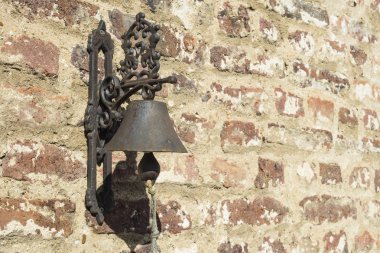 Bir tuğla duvara eski demir çan yerleştirilmiş.