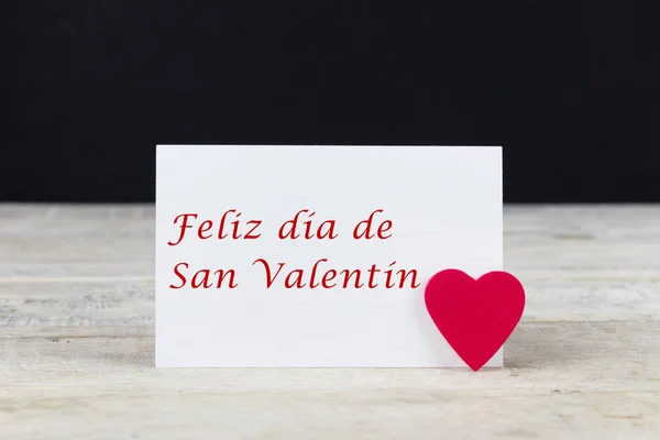 Valentine greeting card on wooden table with text written in spanish \