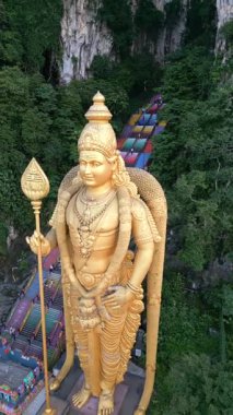 Malezya 'daki Batu Mağaraları' ndaki altın Murugan heykelinin havadan görünüşü. Rengarenk merdivenleri, kireçtaşı uçurumları ve yemyeşil alanları seyahat ve kültürel temalar için idealdir..