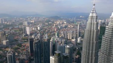 Kuala Lumpur, Malezya 'nın havadan panoramik görüntüsü. Modern gökdelenler ve uzak mesafede dağları olan yoğun şehir manzarası. Kentsel manzara, mimari, seyahat ve Güneydoğu Asya temaları.