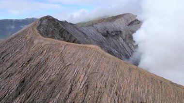 Doğu Java, Endonezya 'daki Bromo Dağı krater sırtı havadan görünüyor. Yürüyüş yolu ve aktif volkandan yükselen dramatik buharı olan manzaralı volkanik bir yer. Seyahat, doğa ve macera temaları.