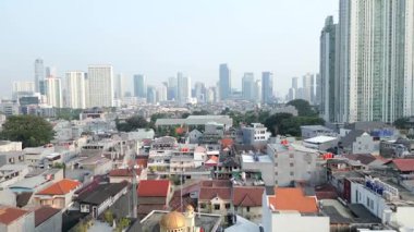 Jakarta şehrinin gökdelenleri geleneksel evlerin üzerine yükselirken gökdelenler görülebiliyor. Endonezya 'nın başkentinde modern mimari ve yoğun düşük katlı yerleşim alanlarının aksine.