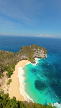 Dramatik uçurumlar, beyaz kum plajları ve Endonezya 'nın Nusa Penida kentindeki Kelingking Sahili' ndeki turkuaz okyanus üzerinde FPV insansız hava aracı uçuşu. Seyahat, yaz ve tropikal macera temaları için ideal.