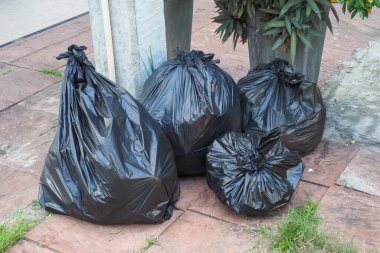 Büyük ve küçük siyah çöp torbaları tamamen mühürlü, 4 torba çimento zeminine konur..