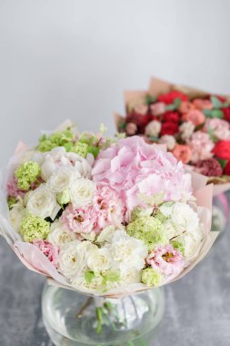 Floristik kavramı. İki gri masaya güzel çiçek buketi. Bahar renkleri. bir çiçek mağazası, çiçekçi iş.