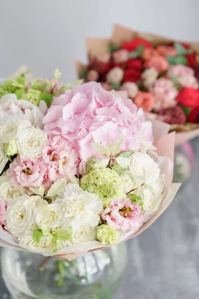 Concepto floristería. Dos ramo de hermosas flores en la mesa gris. Colores de primavera. el trabajo de la floristería en una floristería . —  Fotos de Stock
