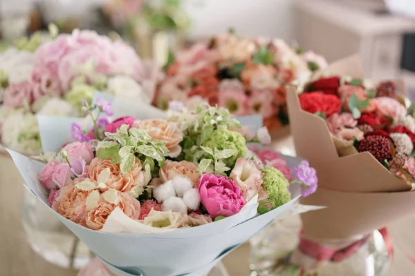 Conceito de floricultura. Quatro buquê de flores bonitas na mesa cinza. Cores de primavera. o trabalho da florista em uma loja de flores . — Fotografia de Stock