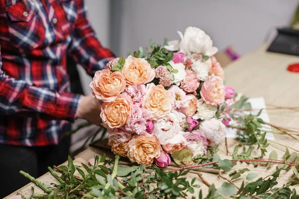 Female florist. Floral workshop - woman making a beautiful flower composition a bouquet. Floristry concept