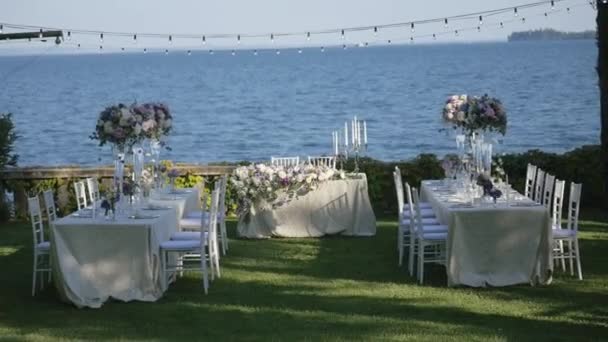 Schöne Tischdekoration mit Geschirr und Blumen für eine Party, Hochzeitsempfang oder andere festliche Veranstaltung. am Ufer des Gardasees, Italien. — Stockvideo