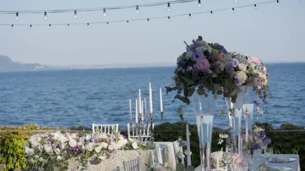 Vacker dukning med porslin och blommor för en fest, bröllop eller annan festlig tillställning. På stranden av Gardasjön, Italien. — Stockvideo