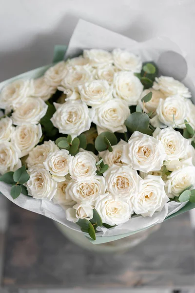 Белые розы из спрея. Букет красивых цветов на деревянном столе. Концепция флористики. работа флориста в цветочном магазине. Вертикальное фото — стоковое фото