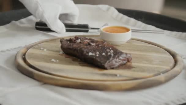 Der Mann im Restaurant schneidet mit einem Messer Steak vom Marmorrind, gegrillt. serviert auf einem Holzbrett. Beefsteak Kochen auf einer Küche. frisches, köstliches, würziges, saftiges Fleisch — Stockvideo