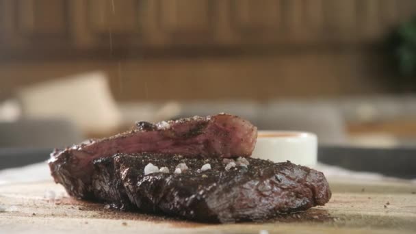 Dochutíme pepřem a solí. Grilování steak na pánev. Hovězí steak vaření v kuchyni. Čerstvé, chutné, pikantní, šťavnaté maso — Stock video