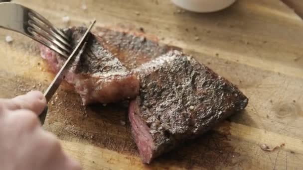 The man in the restaurant with a knife cuts steak of marble beef, grilled. Serving on a wooden Board. Beefsteak cooking on a kitchen. Fresh, delicious, spicy, juicy meat — Stock Video
