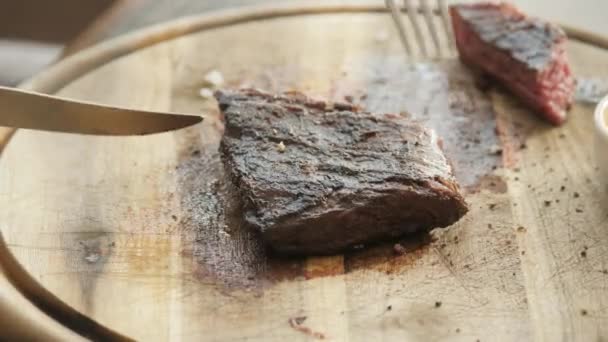 Der Mann im Restaurant schneidet mit einem Messer Steak vom Marmorrind, gegrillt. serviert auf einem Holzbrett. Beefsteak Kochen auf einer Küche. frisches, köstliches, würziges, saftiges Fleisch — Stockvideo