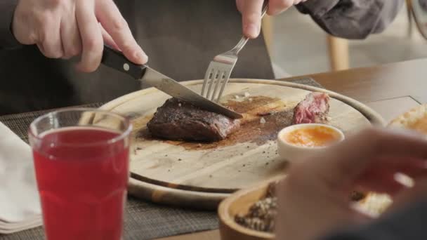 De man in het restaurant met een mes snijdt van marmeren rundvlees, gegrilde biefstuk. Die dienst doen op een houten plank. Biefstuk koken op een keuken. Vers, lekker, pittige, sappige vlees — Stockvideo