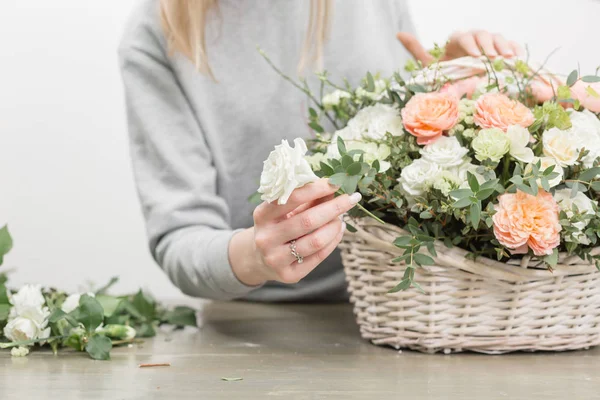 Närbild händer kvinnliga florist. Blommig workshop - kvinnan att göra en vacker blomma sammansättning en bukett i en korg. Blomsterhandlare koncept — Stockfoto