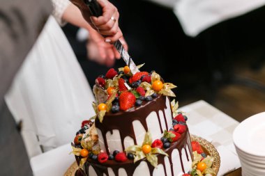 Ahşap masa üzerinde çilek ile düğün pastası. Gelin ve damat ziyafet restoran tatlı pasta kesti.