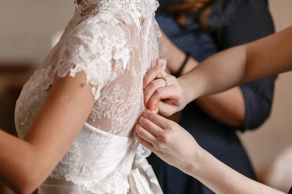 Kleidung eines Hochzeitskleides. Brautjungfer bindet Schleife auf weißem Kleid. Braut wartet — Stockfoto
