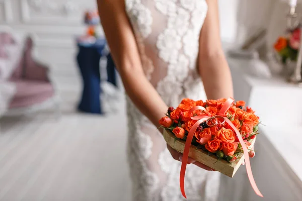 Δύο χρυσά δαχτυλίδια γάμου τοποθέτηση θήκη από πορτοκαλί τριαντάφυλλα. στα χέρια των γυναικών. Αξεσουάρ για τη νύφη και το γαμπρό. Προετοιμασία για την τελετή — Φωτογραφία Αρχείου