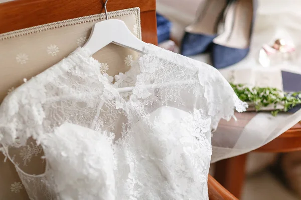 Белое свадебное платье с кружевами, лежащими на стуле. букет разных цветов. Современная свадебная компания с цветком мака и чертополохом. аксессуары для невесты на столе — стоковое фото