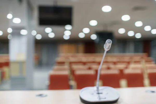 Micrófono en primer plano. Presentación del seminario. Sala de conferencias llena de asientos vacíos. Color rojo. Salón de talleres y seminarios — Foto de Stock