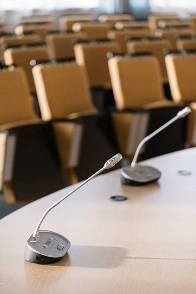 Microphone in the foreground. Seminar presentation. Conference room full of empty seats. Red color. Hall for workshops and seminars — Stock Photo, Image