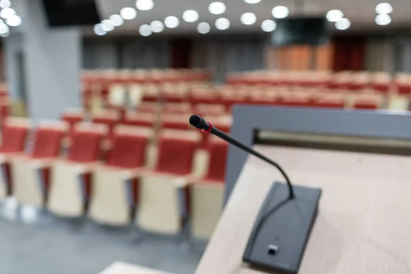 Microphone in the foreground. Seminar presentation. Conference room full of empty seats. Red color. Hall for workshops and seminars — Stock Photo, Image