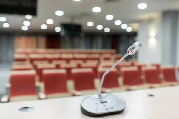 Microphone in the foreground. Seminar presentation. Conference room full of empty seats. Red color. Hall for workshops and seminars — Stock Photo, Image