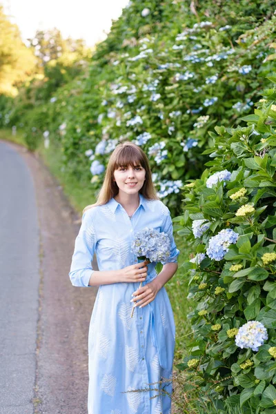 Hortênsia jardinagem. Retrato de jovem mulher bonita em vestido azul longo no parque de flores mágicas em São Miguel, Açores. Portugal . — Fotografia de Stock