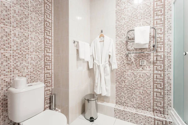 Casa de banho Dentro de quartos de um apartamento ou hotel. Toalha branca limpa e roupão de banho em um cabide preparado para usar . — Fotografia de Stock