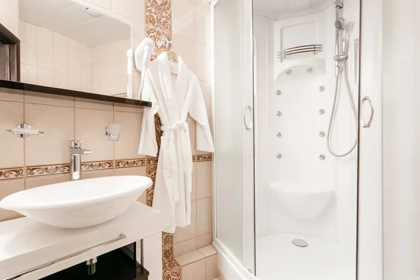 Casa de banho Dentro de quartos de um apartamento ou hotel. Toalha branca limpa e roupão de banho em um cabide preparado para usar . — Fotografia de Stock