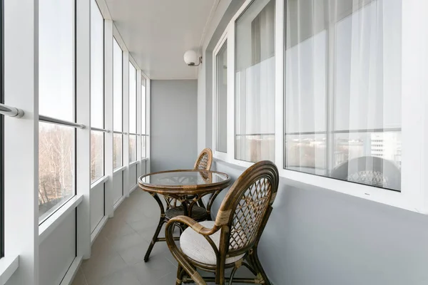 Glastisch und Korbsessel aus Rattan. Korbmöbel Rattantisch zwei Stühle neben dem Fenster auf dem Balkon — Stockfoto