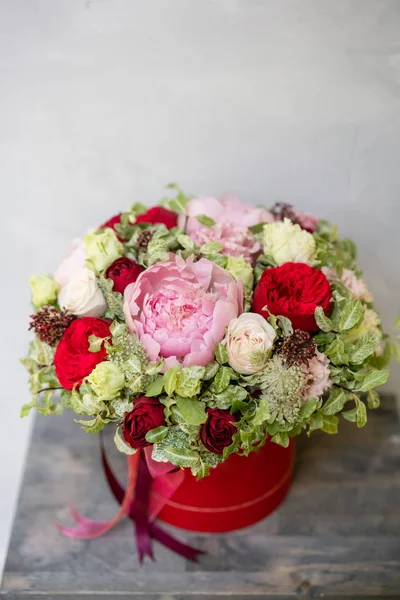 Beautiful spring bouquet in head box. Arrangement with mix flowers. The concept of a flower shop, a small family business. Red color. Work florist.