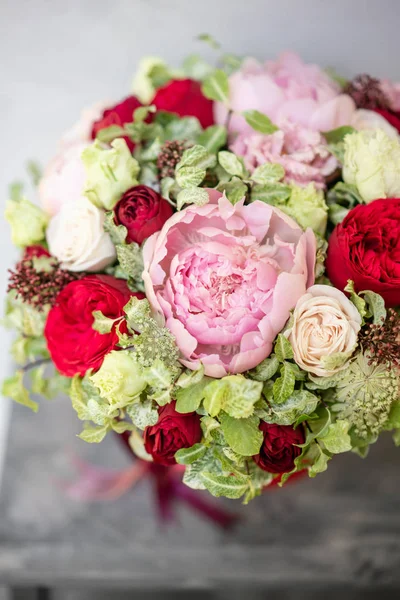 Beautiful spring bouquet in head box. Arrangement with mix flowers. The concept of a flower shop, a small family business. Red color. Work florist.