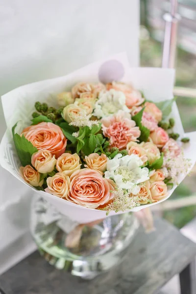 Work florist. Beautiful spring bouquet. Arrangement with mix flowers. The concept of a flower shop, a small family business. Color light peach and orange