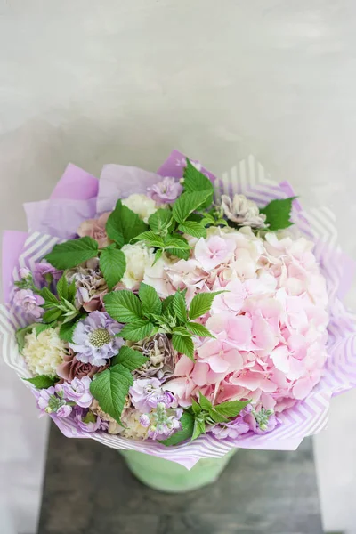 Floristin arbeiten. schöner Frühlingsstrauß. Arrangement mit Mischblumen. das Konzept eines Blumenladens, eines kleinen Familienunternehmens. Farbe hellrosa und lila. — Stockfoto