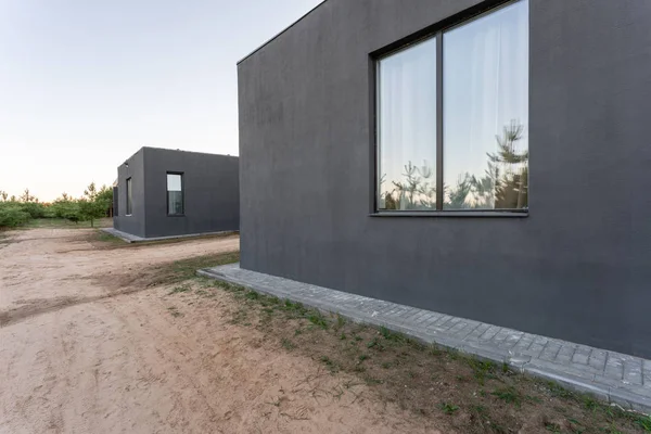 Vista laterale di una veranda aperta di fronte a un moderno cottage forestale. Pineta giovane foresta sotto i raggi del tramonto sullo sfondo . — Foto Stock